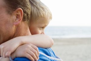 closeup of a sun hugging his father on the shore