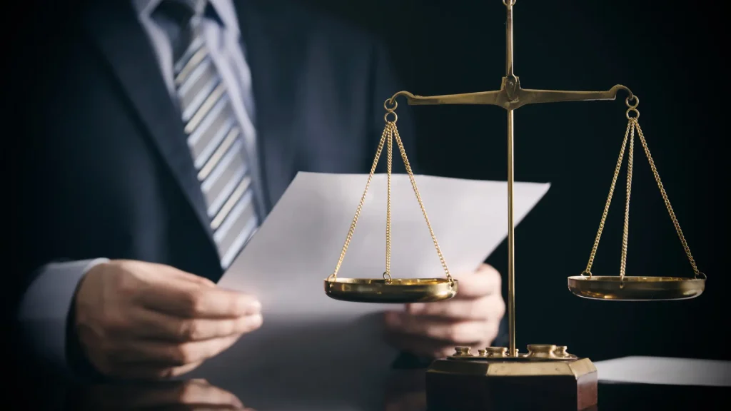 A man in a suit holds a paper and a scale, symbolizing professionalism and balance in decision-making.