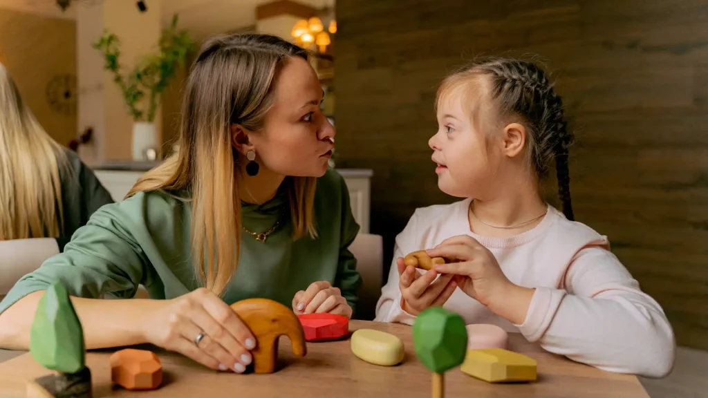 Woman interacting with child with Down syndrome during play