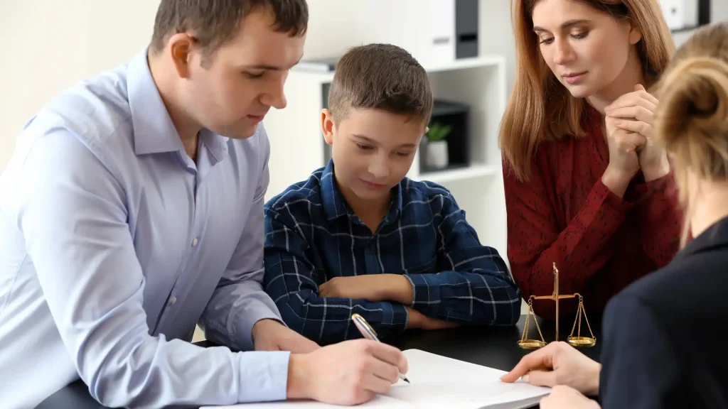Family sitting at a table and signing legal documents together.